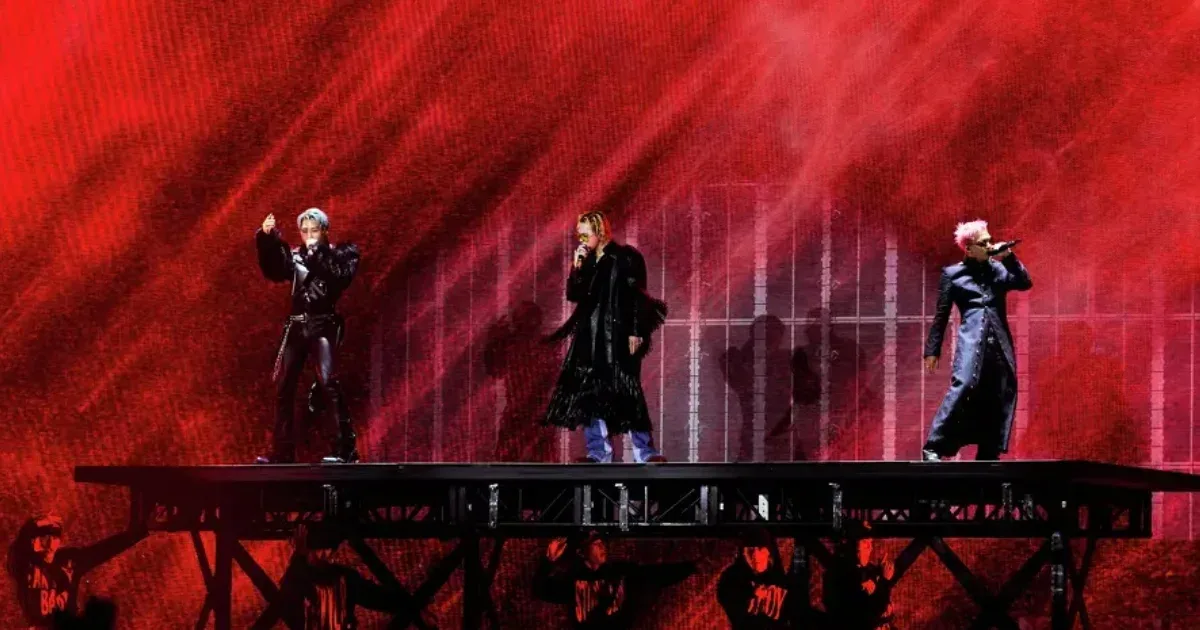 BIGBANG em apresentação em um palco iluminado de vermelho.