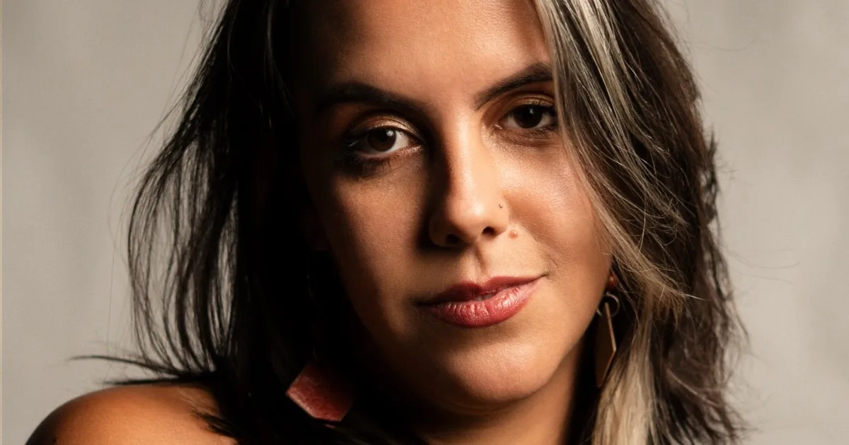 Retrato de Mari Ruberti com cabelos escuros e fundo suave.