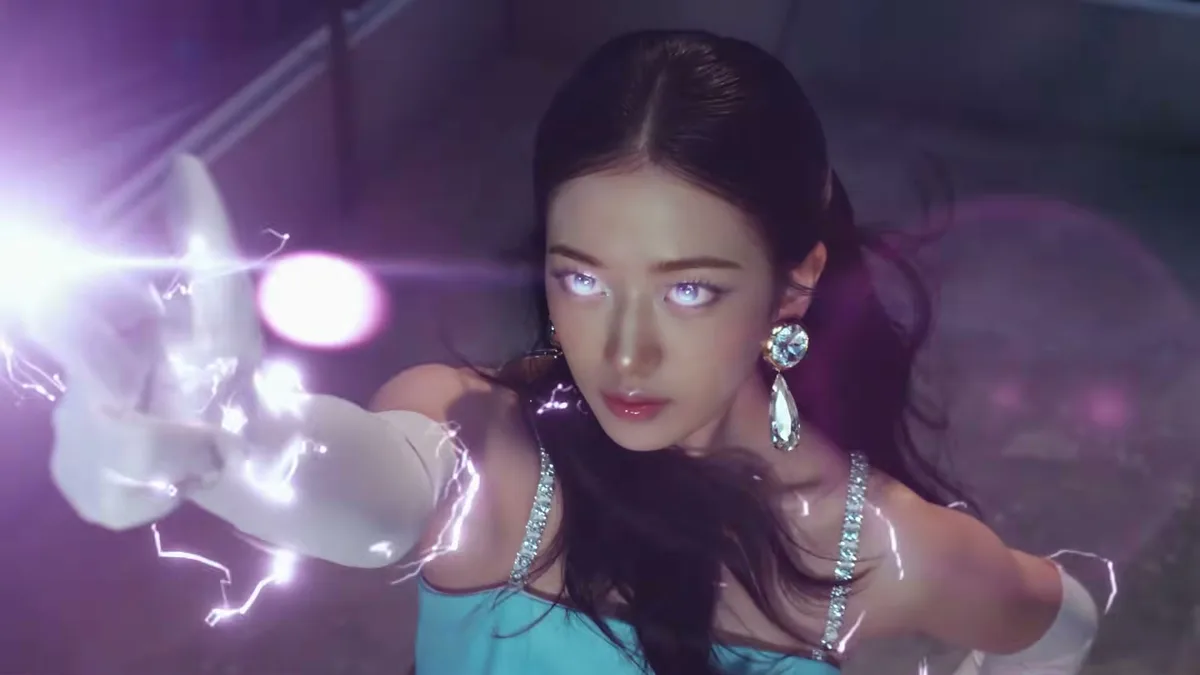 Integrante do IVE em cena de fantasia do clipe Looks Can Kill, com brilho nos olhos e efeito luminoso na mão