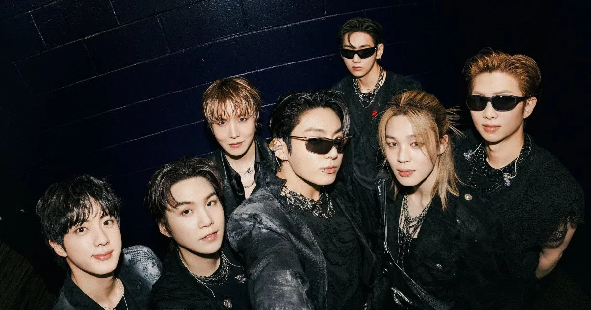 Os sete integrantes do BTS em retrato promocional com roupas escuras